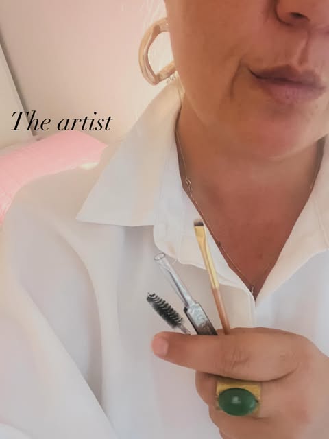 Jennifer en chemise blanche tenant ses pinceaux à sourcils